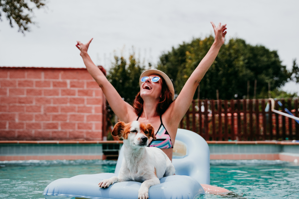woman in swimming pool on a raft with her dog