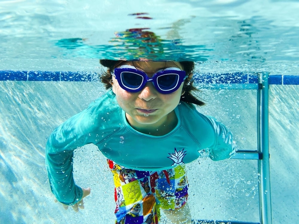 Little boy splashing in a well-maintained Florida pool, illustrating the benefits of January pool maintenance in Florida