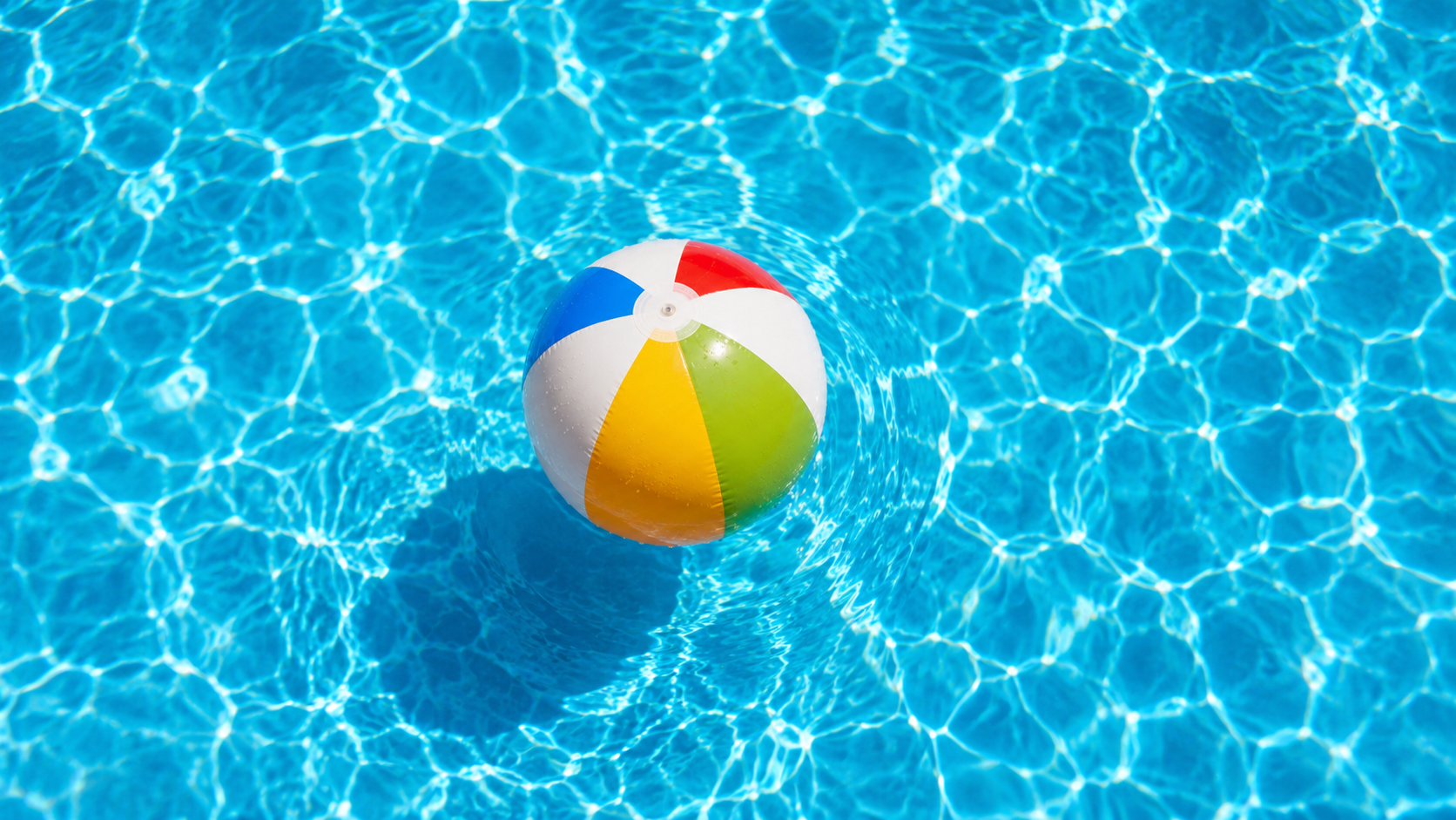 Pool party cleanup Orlando shown by a single colorful beach ball floating in clear blue pool water after a busy summer weekend.