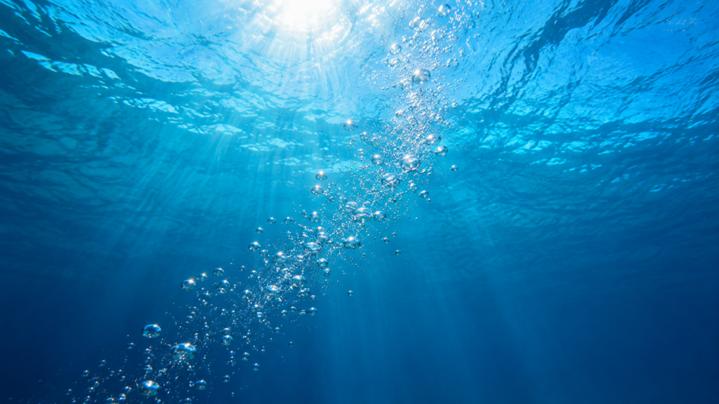 Air bubbles in pool water shown by a stream of silver bubbles rising through clear blue water in an Orlando residential pool.