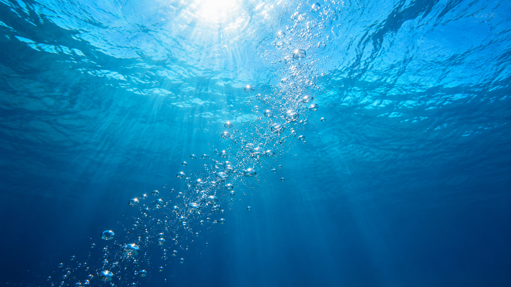 Air bubbles in pool water shown by a stream of silver bubbles rising through clear blue water in an Orlando residential pool.