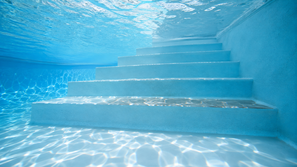 Slippery pool steps shown by a subtle glossy buildup along one submerged step in a clear Orlando residential swimming pool.