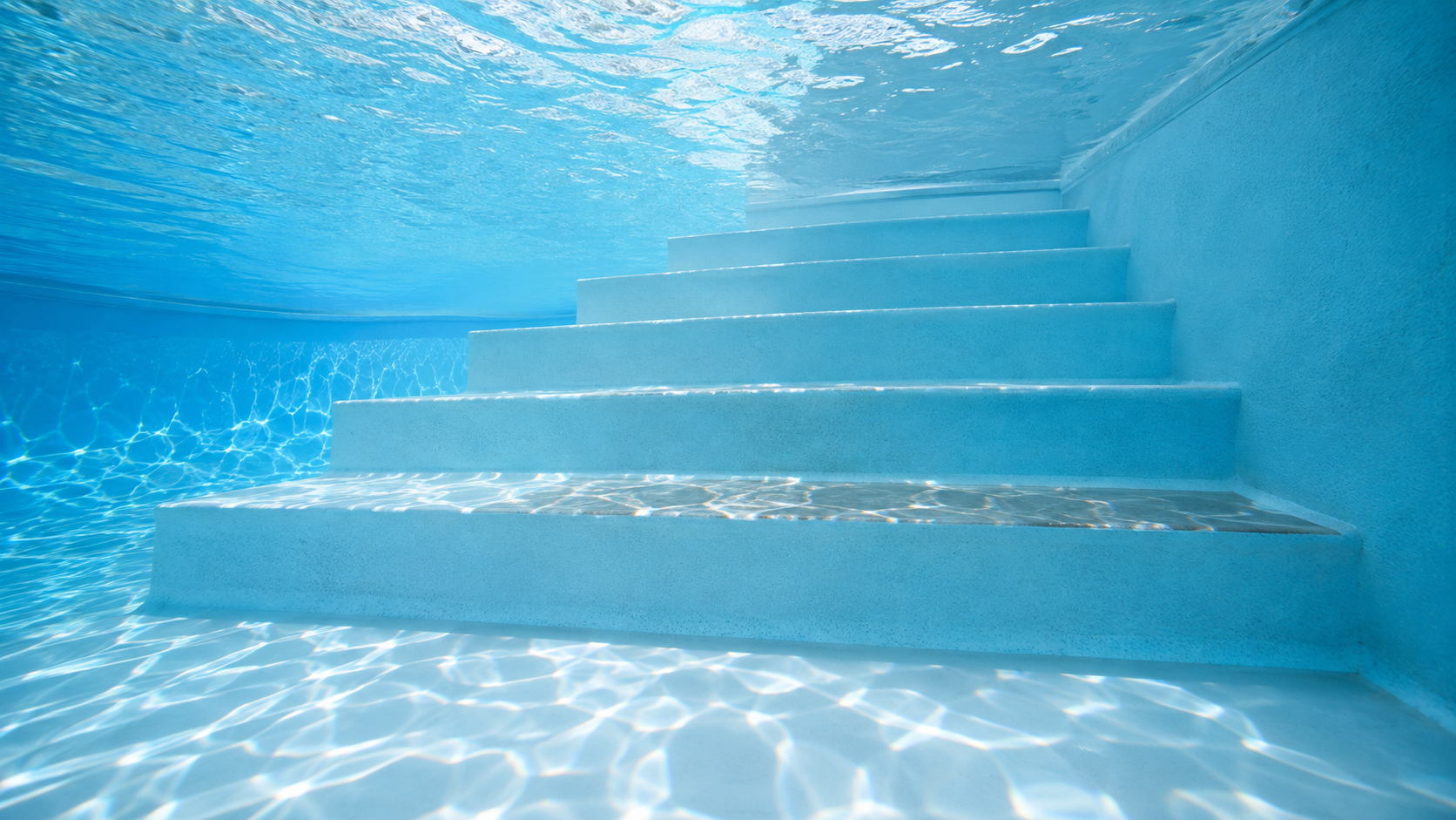 Slippery pool steps shown by a subtle glossy buildup along one submerged step in a clear Orlando residential swimming pool.
